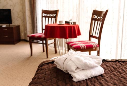 a room with a table and chairs and a towel on a bed at Golden Palace in Aktau