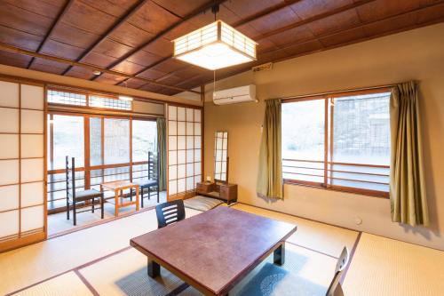 um quarto com uma mesa, cadeiras e janelas em Yushintei em Hakone