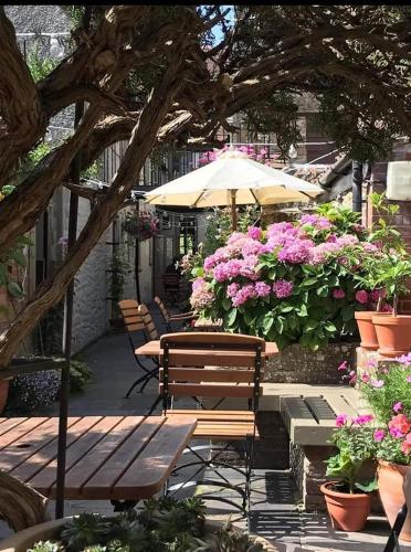 a patio with benches and flowers and an umbrella at The Plume of Feathers in Sherborne