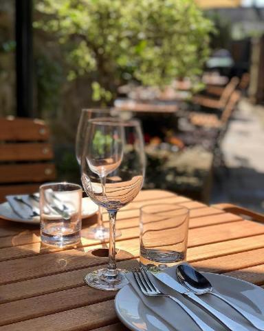 a wooden table with wine glasses and plates and silverware at The Plume of Feathers in Sherborne