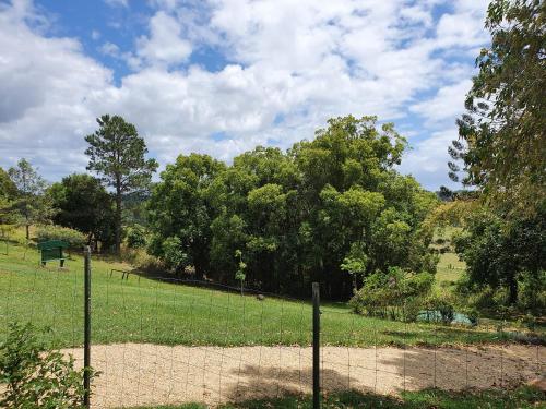 a fence in a field with trees in the background at Tropical Coast Retreat - Pet Friendly - Adult only in Kingscliff