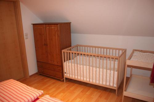 a bedroom with a crib and a wooden cabinet at Haus-Maria-Magdalena in Bad Lauterberg