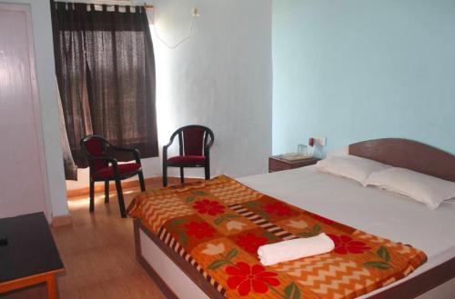 a bedroom with a bed with two chairs and a window at Arya Beach resort in Mandarmoni