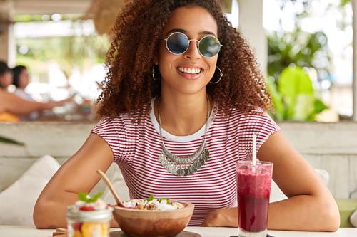 a woman sitting at a table with a bowl of food and a drink at Hotel Caribe - Garda Lake Collection in Brenzone sul Garda