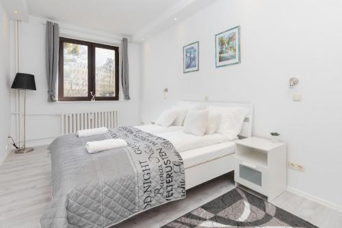 a white bedroom with a bed and a window at Apartments Riviera Świętojańska by Renters in Gdynia