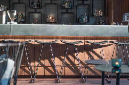a bar with four stools in front of a counter at Motel One Hamburg Airport in Hamburg