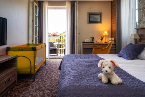 a teddy bear sitting on a bed in a hotel room at Korona Hotel in Ostrołęka