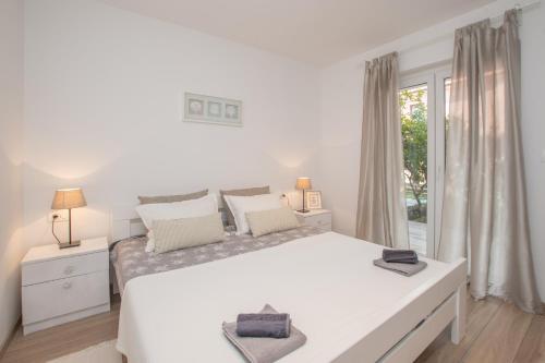 a white bedroom with a large bed and a window at Apartments Lirio in Umag