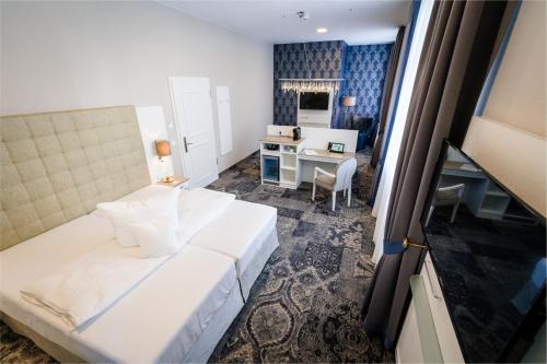 Schlafzimmer mit einem weißen Bett und einem Schreibtisch in der Unterkunft Schlosshotel Bad Neustadt in Bad Neustadt an der Saale