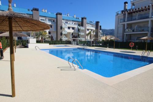 uma piscina com um guarda-sol e alguns edifícios em 0705 Ap Victoria I em Denia
