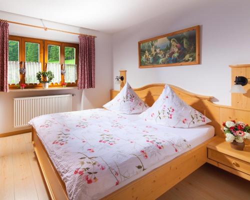 Un dormitorio con una cama blanca con flores. en Haus Michinglehen en Marktschellenberg