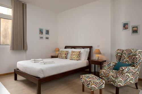 un dormitorio con una cama y una silla en Ribeira das Casas Apartments by Homie, en Funchal