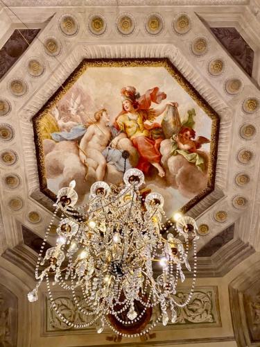 a chandelier hanging from a ceiling with a painting at Hotel Martelli in Florence