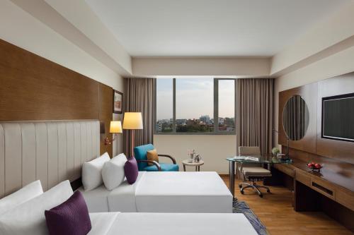 a hotel room with two beds and a desk at Vivanta Thiruvananthapuram in Trivandrum