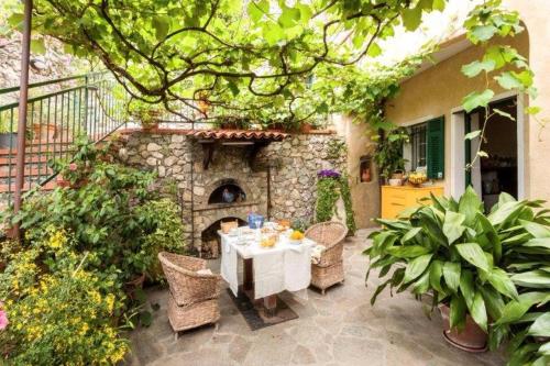 a patio with a table and chairs and a stone fireplace at agriturismo la selva in Finale Ligure