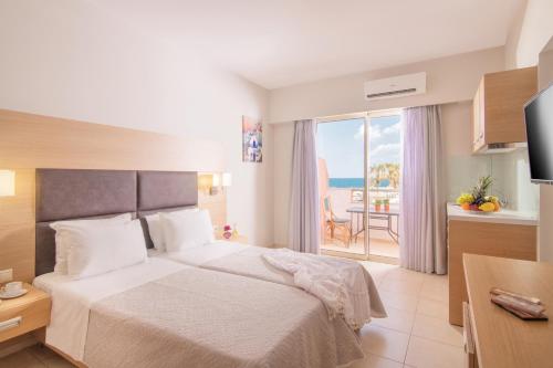 a bedroom with a bed and a view of the ocean at Pleasure Beach Hotel in Malia
