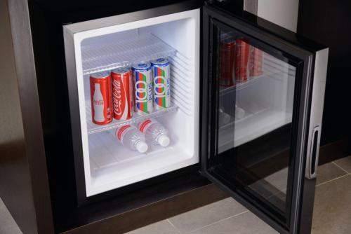 an open refrigerator filled with cocacola drinks at ERNES Hotel in Perai