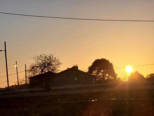 a sunset over a house with the sun in the sky at Hotel Restaurante el Fornon in Novellana