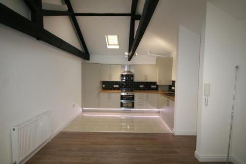 a kitchen with white walls and wooden floors at Flat 5, 124 High Street in Newmarket