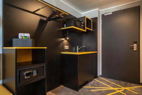 een badkamer met zwarte muren en een wastafel en gele planken bij the niu Fury - Apartments in Aschheim
