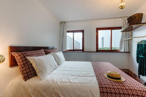 a bedroom with a large white bed with two windows at THE MODERNIST, Architecture experience in Faro