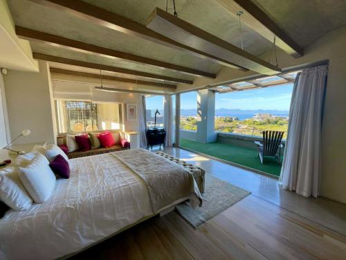 a bedroom with a large bed and a large window at Beach End Plettenberg Bay in Plettenberg Bay