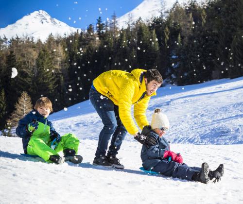 a woman and two children playing in the snow at Hôtel Club mmv Le Val Cenis *** in Lanslebourg-Mont-Cenis