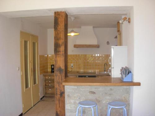 una cocina con barra y dos taburetes. en Mas la Vitalis Chambres D'Hôtes, en LʼIsle-sur-la-Sorgue