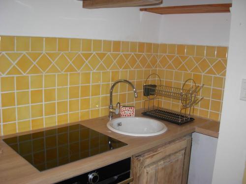 a bathroom with a sink and a yellow tiled wall at Mas la Vitalis Chambres D'Hôtes in L'Isle-sur-la-Sorgue