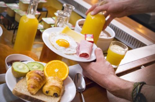 a person is holding a plate of breakfast food at Hôtel Club mmv Le Val Cenis *** in Lanslebourg-Mont-Cenis