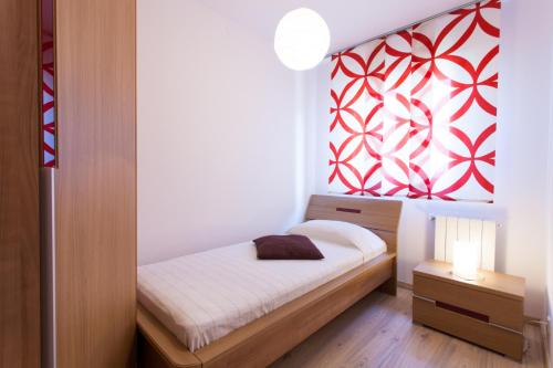 a small bedroom with a bed and a red and white wall at Apartments Banić in Poreč