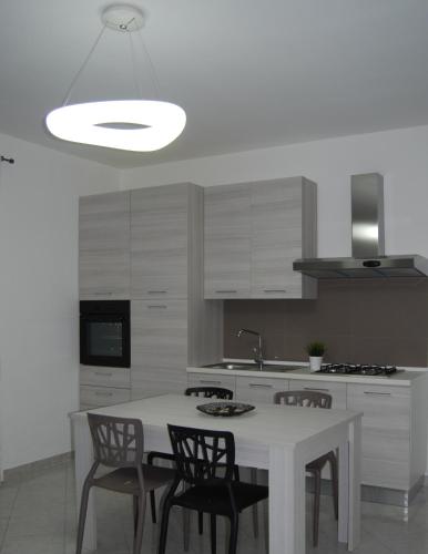 a white kitchen with a white table and chairs at Focu e Mari in Mascali