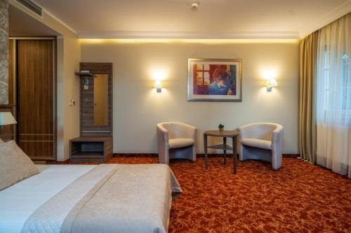 a hotel room with a bed and two chairs at Korona Hotel in Ostrołęka