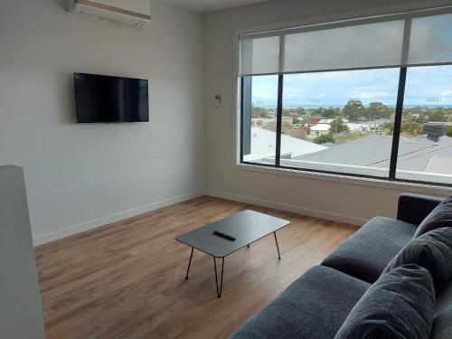a living room with a couch and a large window at Waterline Property Portarlington in Portarlington