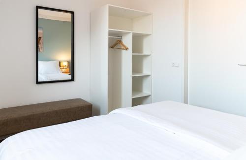 a bedroom with a white bed and a mirror at Boutique Resort Schaardijk vakantiewoning in Scharendijke