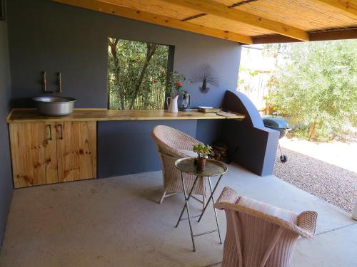 a kitchen with a counter with chairs and a table at Olive Grove Pip in Prince Albert