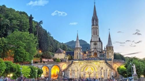 an old building with a church with a clock tower at Hôtel Angelic in Lourdes