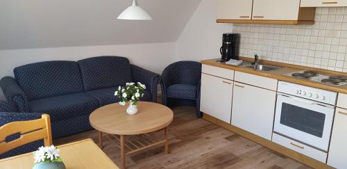 ein Wohnzimmer mit einem Sofa und einem Tisch mit Blumen in der Unterkunft Landhaus Braband Ferienwohnungen - Gustav-Schönleber-Weg 2 in Cuxhaven