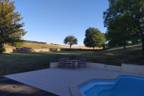 un patio avec une table et des chaises à côté d'une piscine dans l'établissement L'Armance - Magnifique Maison typique morvan avec piscine, à Nuars