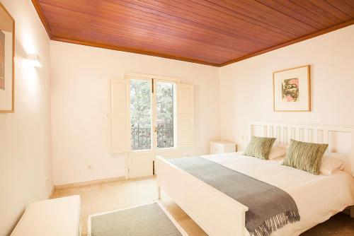 Habitación blanca con cama y ventana en Sa Casa des Mirador, en Fornalutx