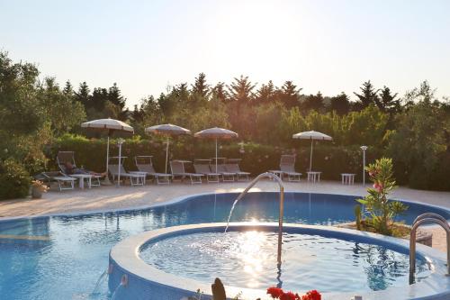 a swimming pool with a fountain and chairs and umbrellas at Agriturismo I Tesori del Sud Vieste, Puglia in Vieste