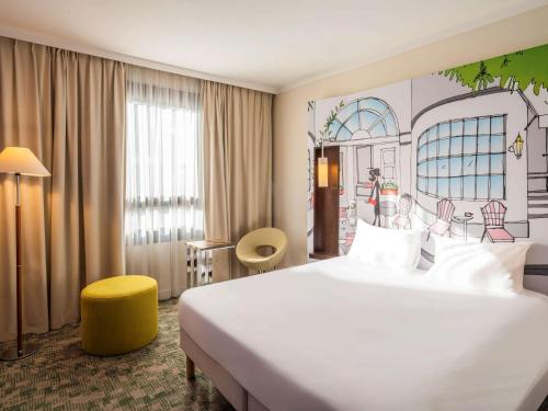 um quarto de hotel com uma grande cama branca e um banco amarelo em ibis Styles Evry Courcouronnes Hotel and Events em Courcouronnes
