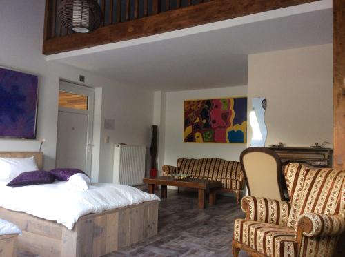 a bedroom with a bed and two chairs and a couch at B&B AntiQua & Qook in Tongeren