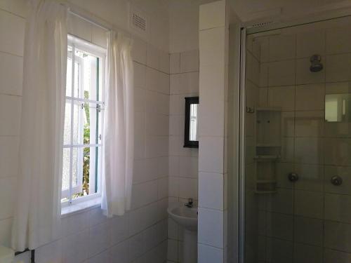 Un baño con ducha, inodoro y ventana. en BillsBest Greengates Cottages, en Port Edward