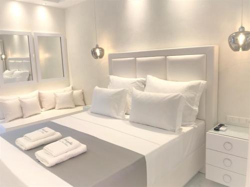 a white bedroom with two white towels on a bed at Amaryllis Luxury Rooms in Platamonas