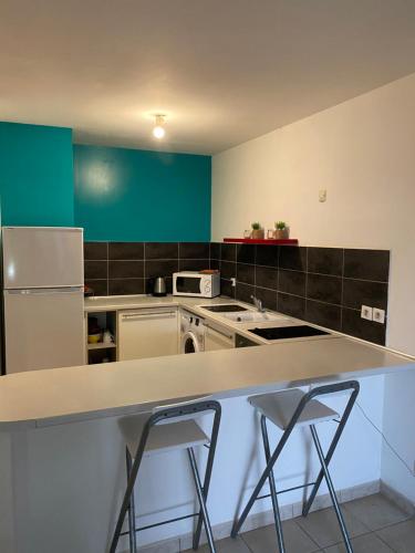 a kitchen with a counter and a refrigerator at Appartement les pieds dans l'eau l'autre bord LE MOULE in Le Moule