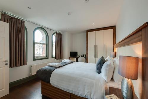 a bedroom with a large bed and two windows at Base Serviced Apartments - Sir Thomas Street in Liverpool