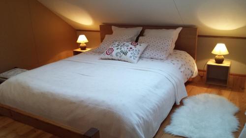 um quarto com uma grande cama branca e 2 candeeiros em Gîte Montrias em Cerfontaine