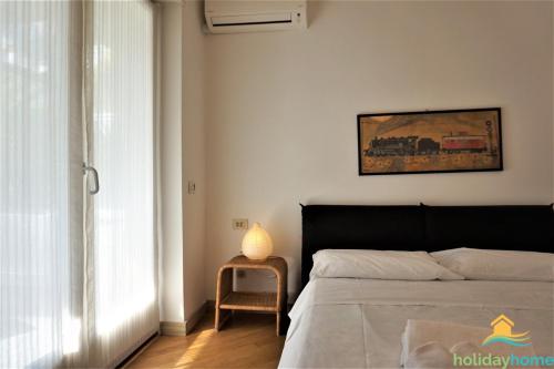 a bedroom with a bed and a table with a lamp at Green relax apartment - Holiday Home Garda Trentino in Riva del Garda