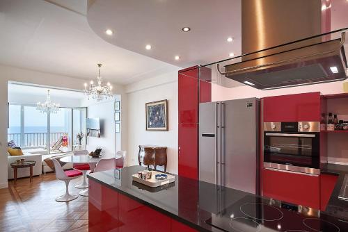 une cuisine avec des placards rouges et un salon dans l'établissement Sunlight Properties - Ruby - the best panoramic sea view in Nice!, à Nice